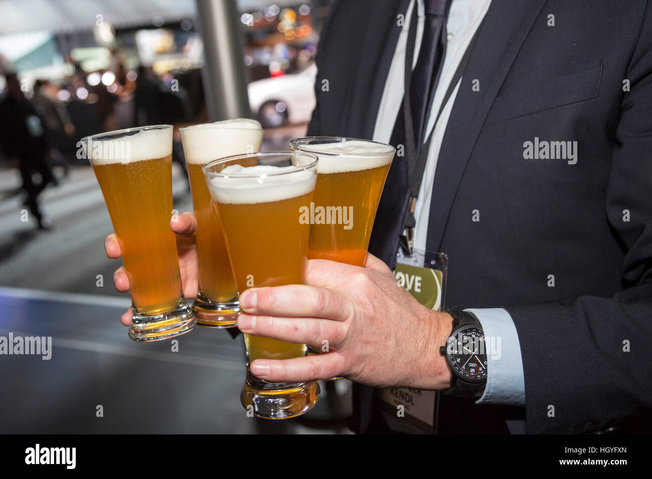 Detroit, Michigan - ein Mann trägt vier Gläser Bier während der Teilnahme an der North American International Auto Show. Stockfoto
