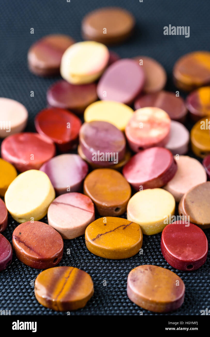 Bunt und poliertem Mookait Jaspis Perlen in ovale Form auf schwarz zu weben. Stockfoto