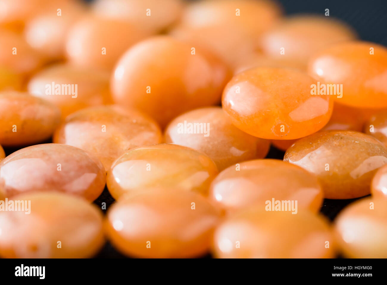 Sammlung von orange Aventurin Münze Perlen auf schwarzem Stoff. Stockfoto