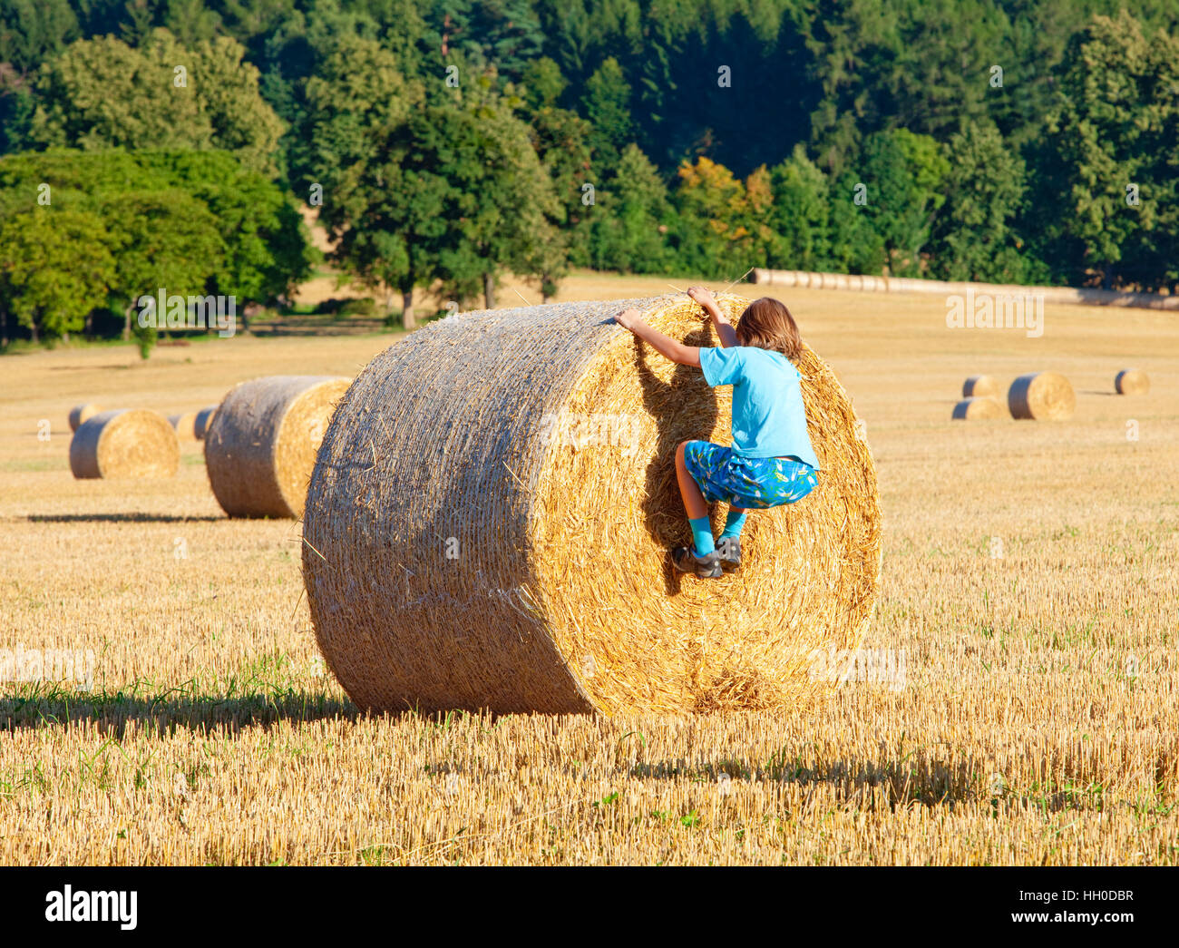 Junge klettern einen Ballen Heu auf einem Feld im Sommer Stockfoto