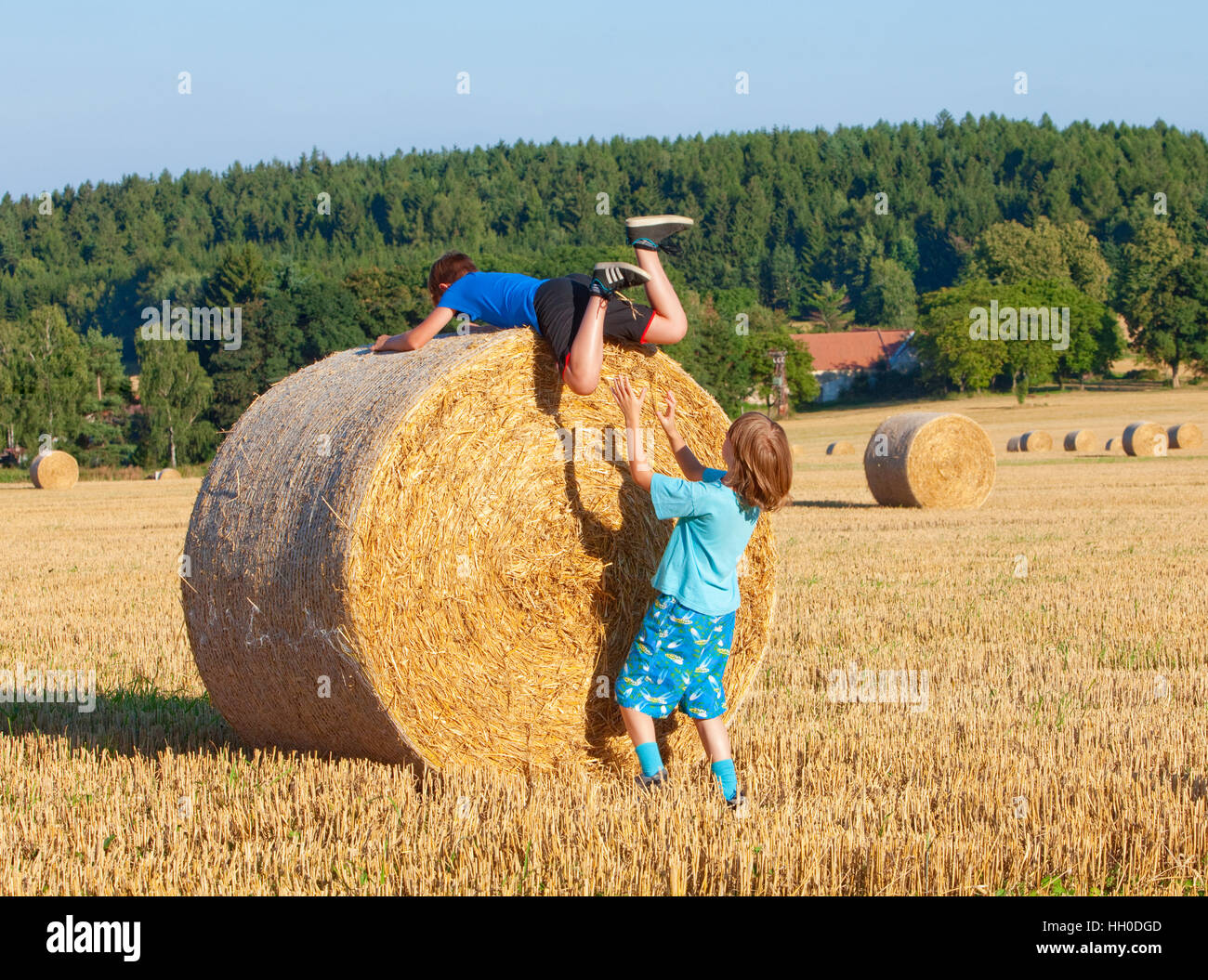 Zwei jungen, die einander helfen, um einen Ballen Heu Klettern Stockfoto