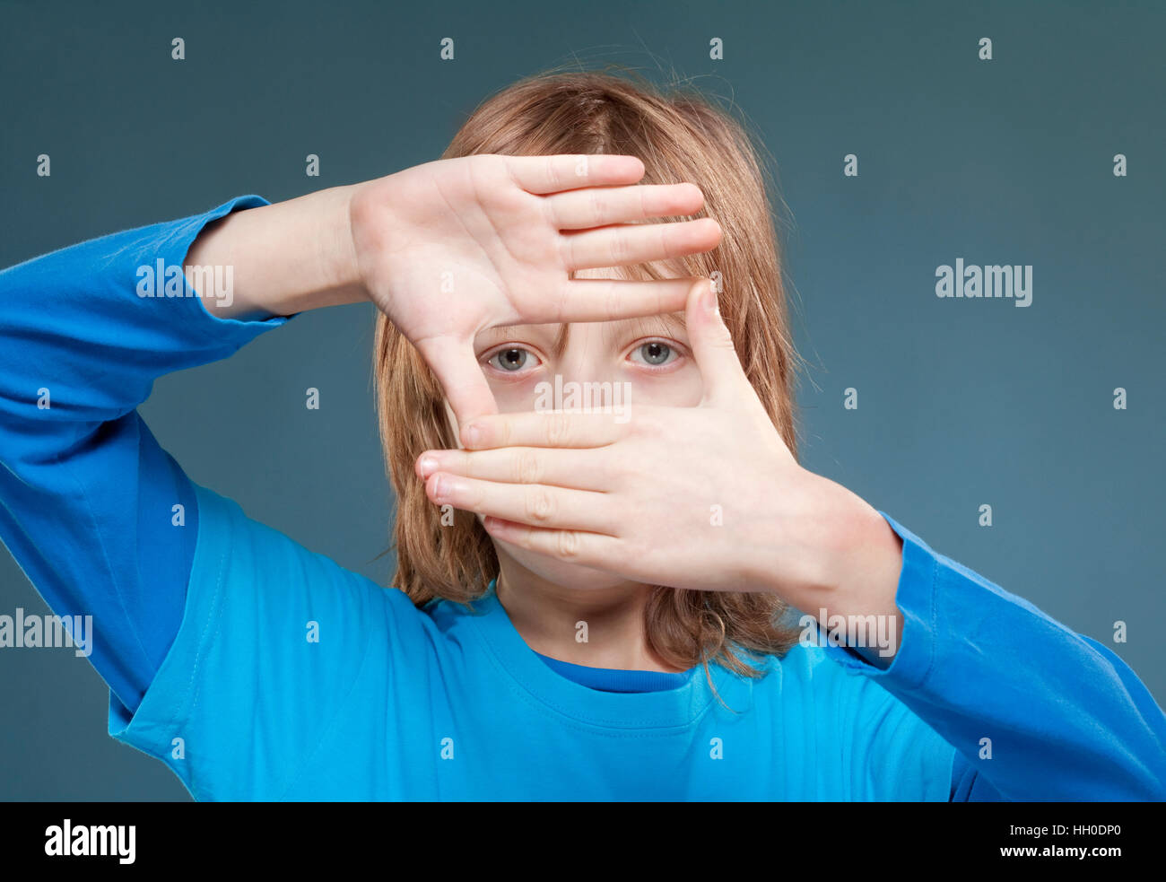 lBoy mit langen blonden Haare auf der Suche durch ein Finger Rahmen Stockfoto