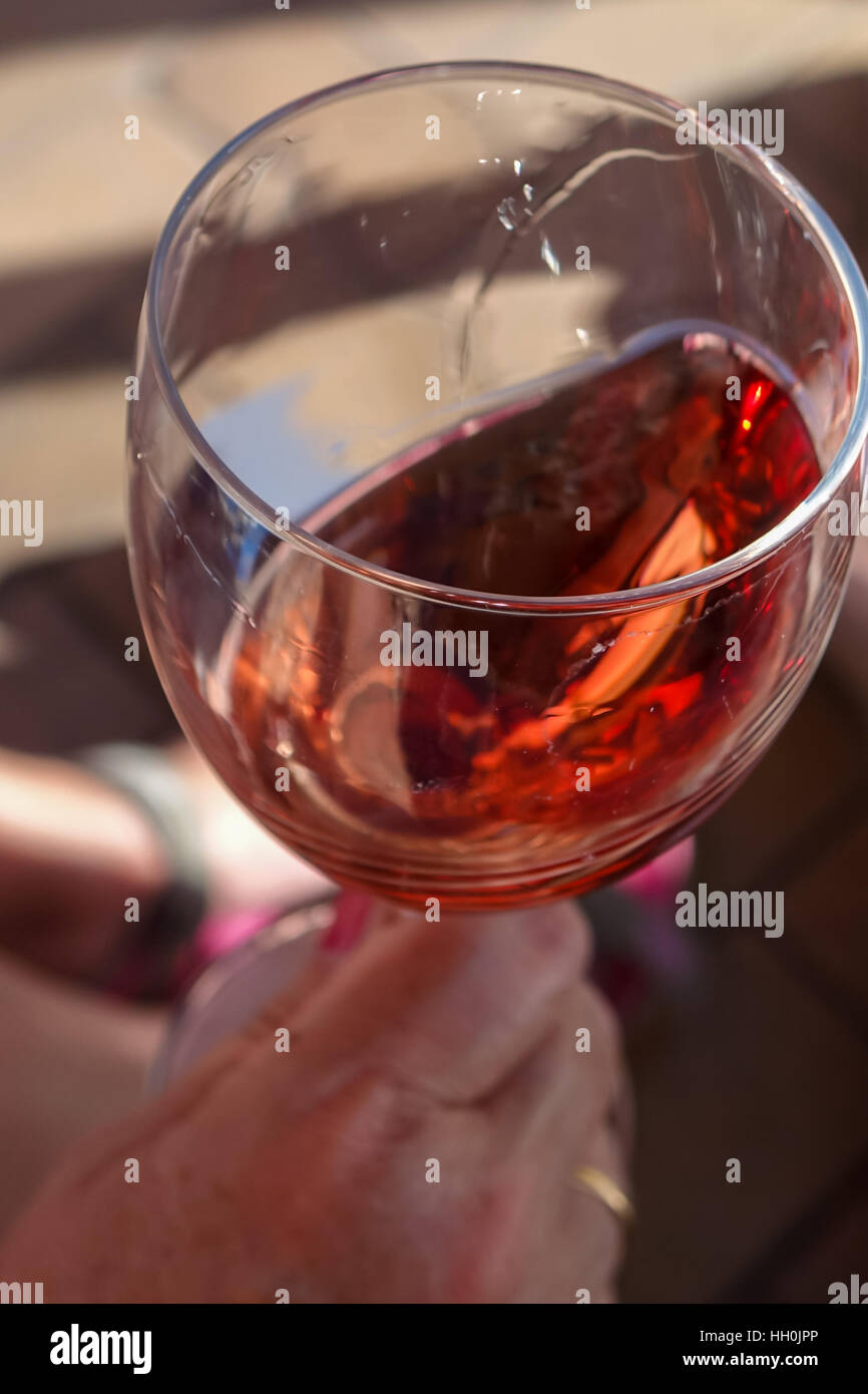 Glas Rose Wein verwirbelt, mit Hand in Schuss Stockfoto