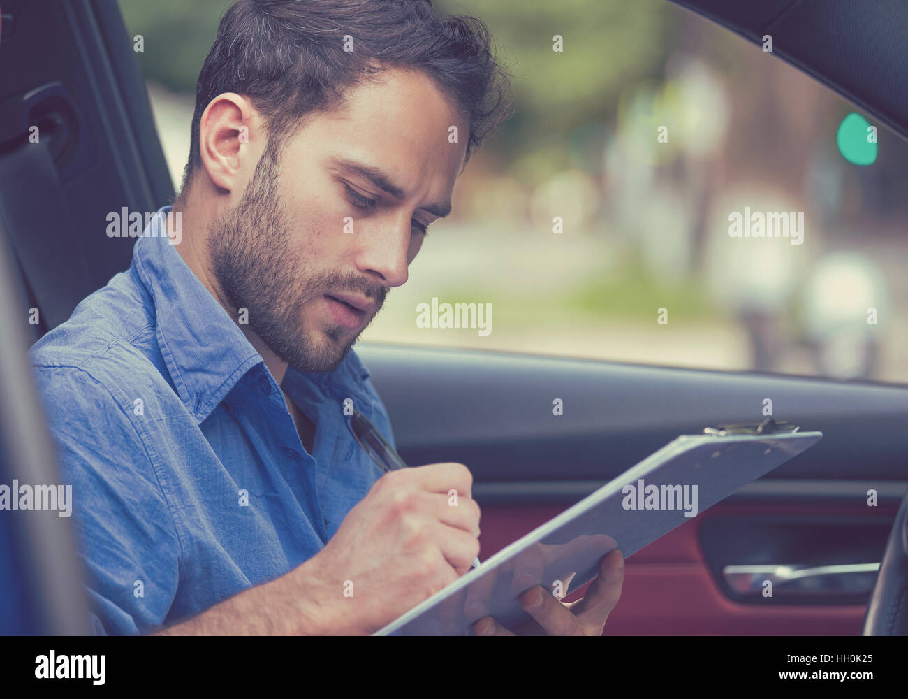 Transport und Besitz Konzept. Schönen jungen Mann im neuen Auto Lesung Signieren von Dokumenten Stockfoto