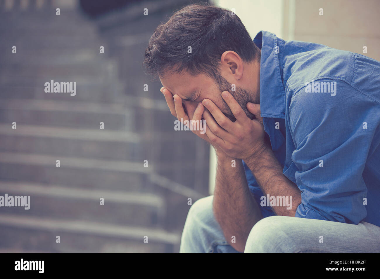 Seitenprofil betont traurig weinende Jüngling sitzt außerhalb Kopf mit den Händen nach unten halten. Menschliche Emotionen Gefühle Stockfoto