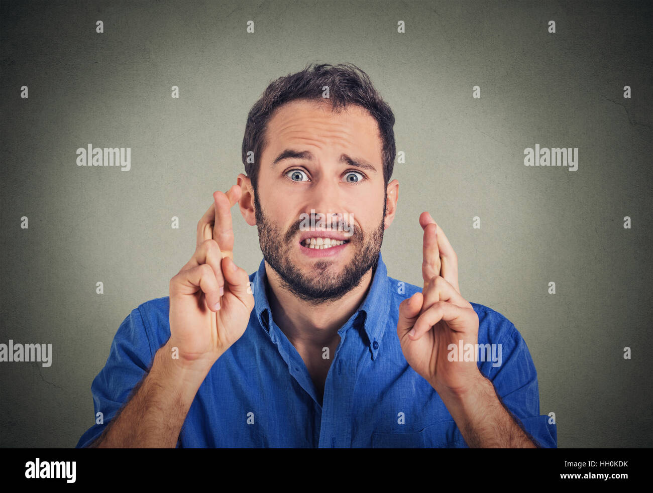 Junger Mann wünschen seinen Daumen auf graue Wand Hintergrund isoliert Stockfoto