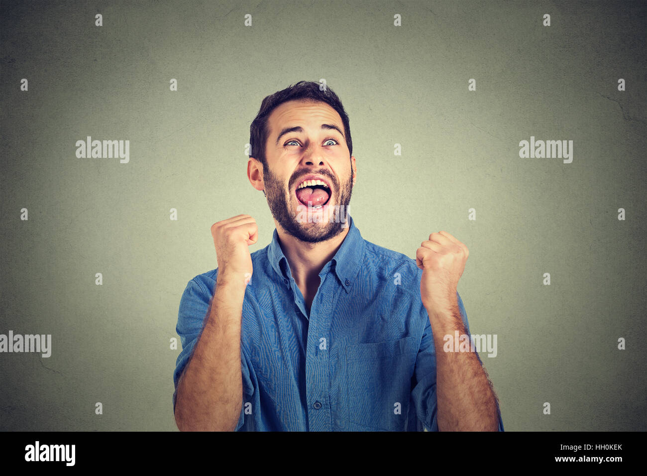 glücklich erfolgreiche studentische Fäuste Geschäftsmann gewinnen gepumpten feiert Erfolg isoliert grau hinterlegt. Positive menschliche emotion Stockfoto