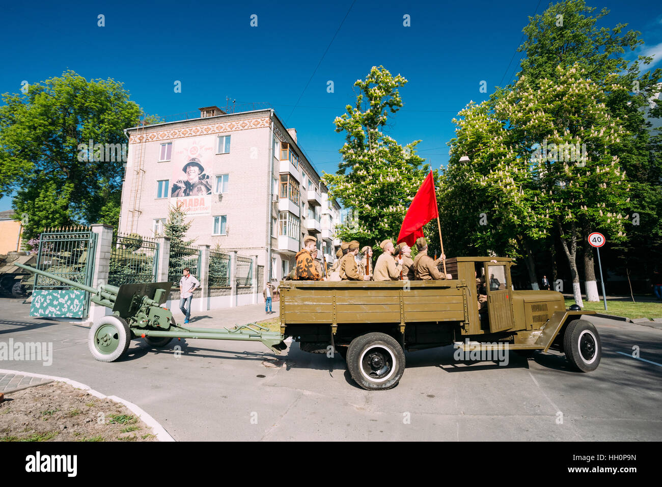 Gomel, Weißrussland - 9. Mai 2016: Russische sowjetische Militär-LKW ZIS-5V mit Männern In Uniform der Soldaten an Bord, Waffe, rote Fahne des 2. Weltkrieges, Abschleppen 57 Mm ZiS-2 Stockfoto