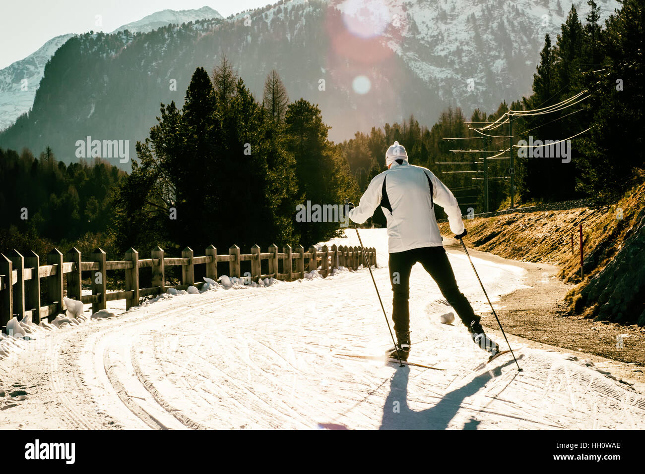 Rückansicht des Mannes in weiße Jacke Skifahren auf sonnigen Tag in Bergen Stockfoto