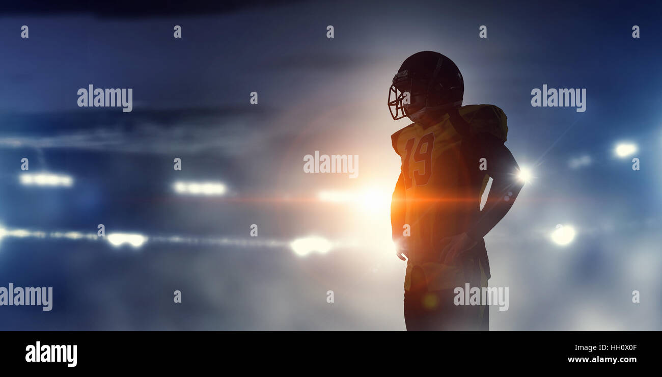 US-amerikanischer American-Football-Spieler gegen die Lichter des Stadions Silhouette. Mixed-media Stockfoto