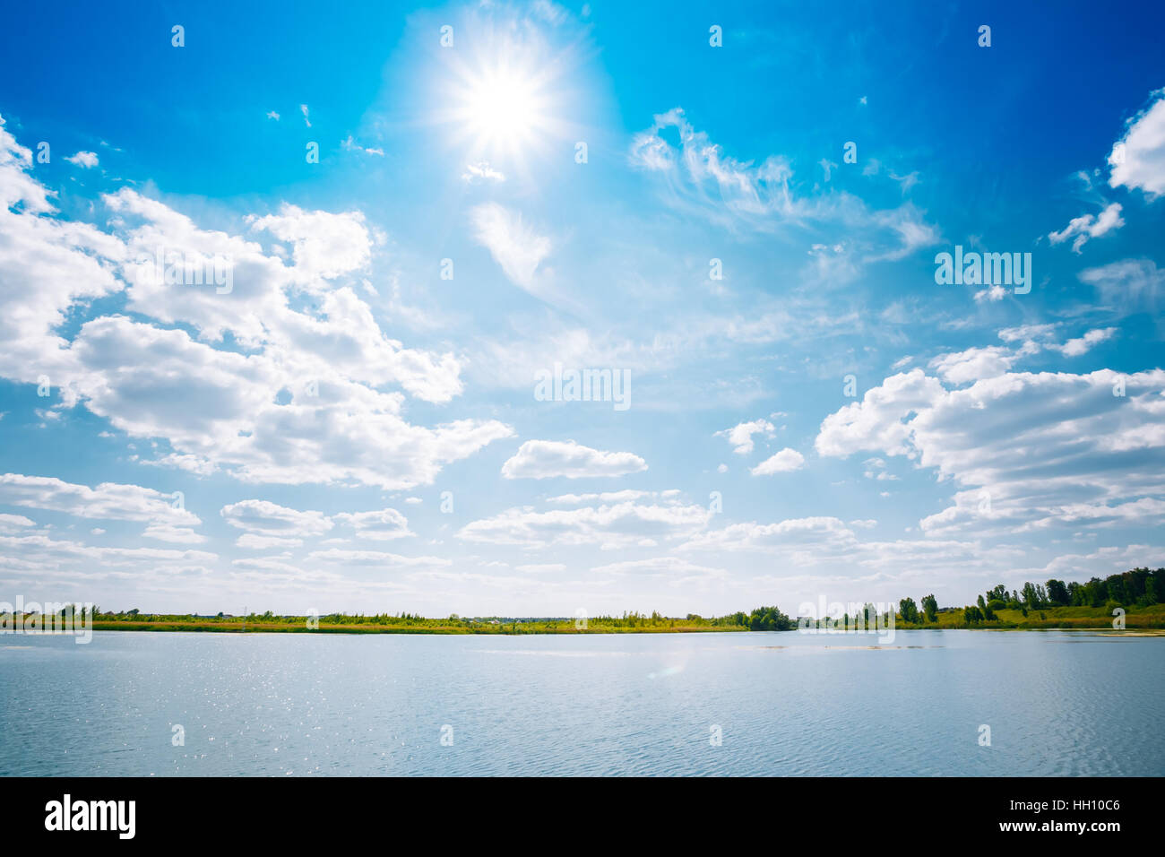 Riverine landschaftlich Skyline, Fluss See Wasserfläche, strahlend blauer Himmel mit weißen Wolken, die Sonne im Zenit. Exemplar Hintergrund. Stockfoto
