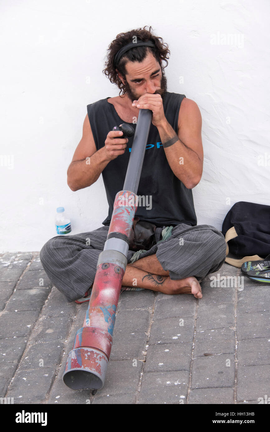 Straßenkünstler unterhält Shopper am Markt das Didgeridoo zu spielen. Stockfoto