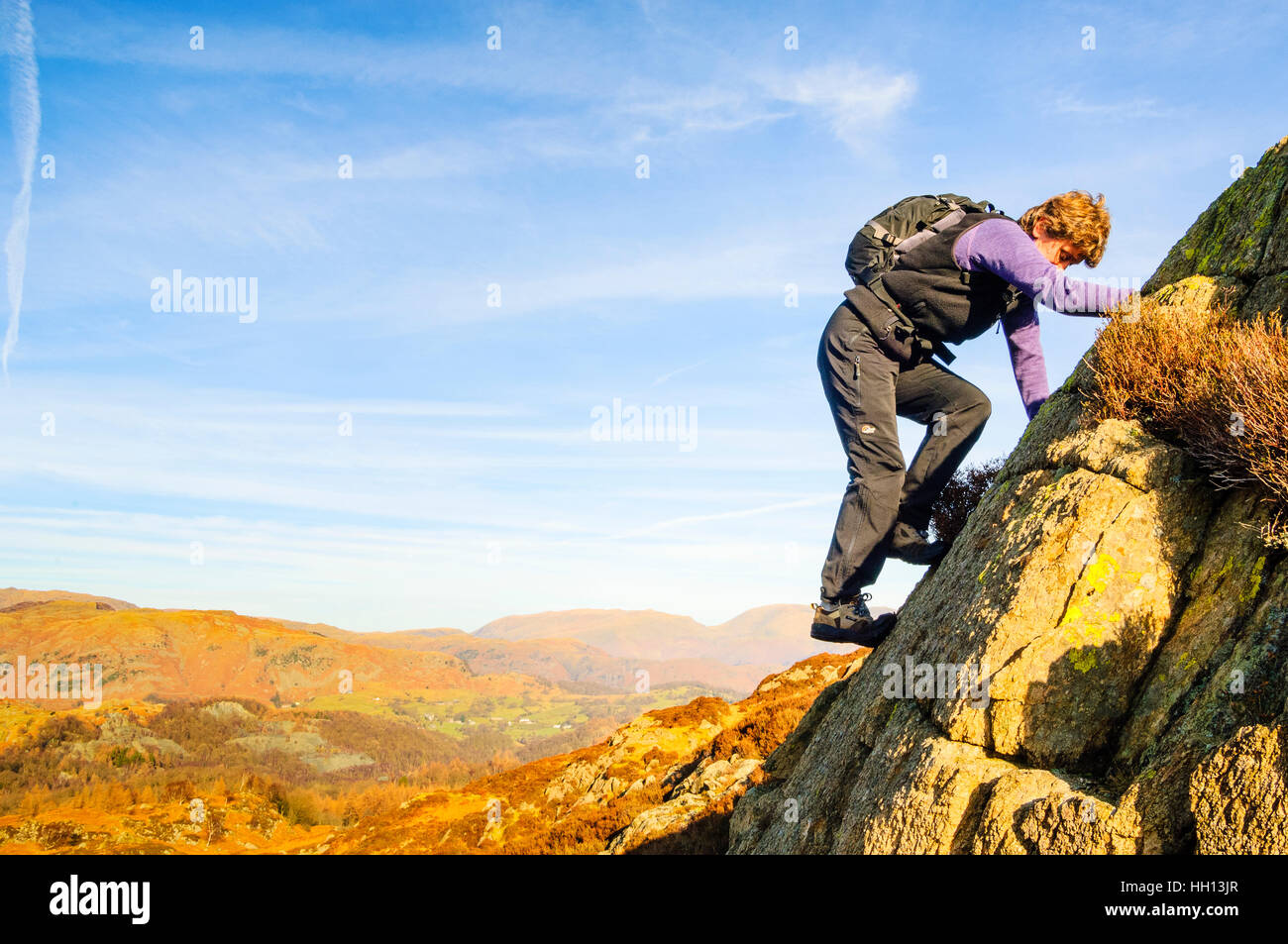 Frau hoch kriechen, auf Raven Felsen oben Yewdale nahe Hawkshead im Lake District Stockfoto