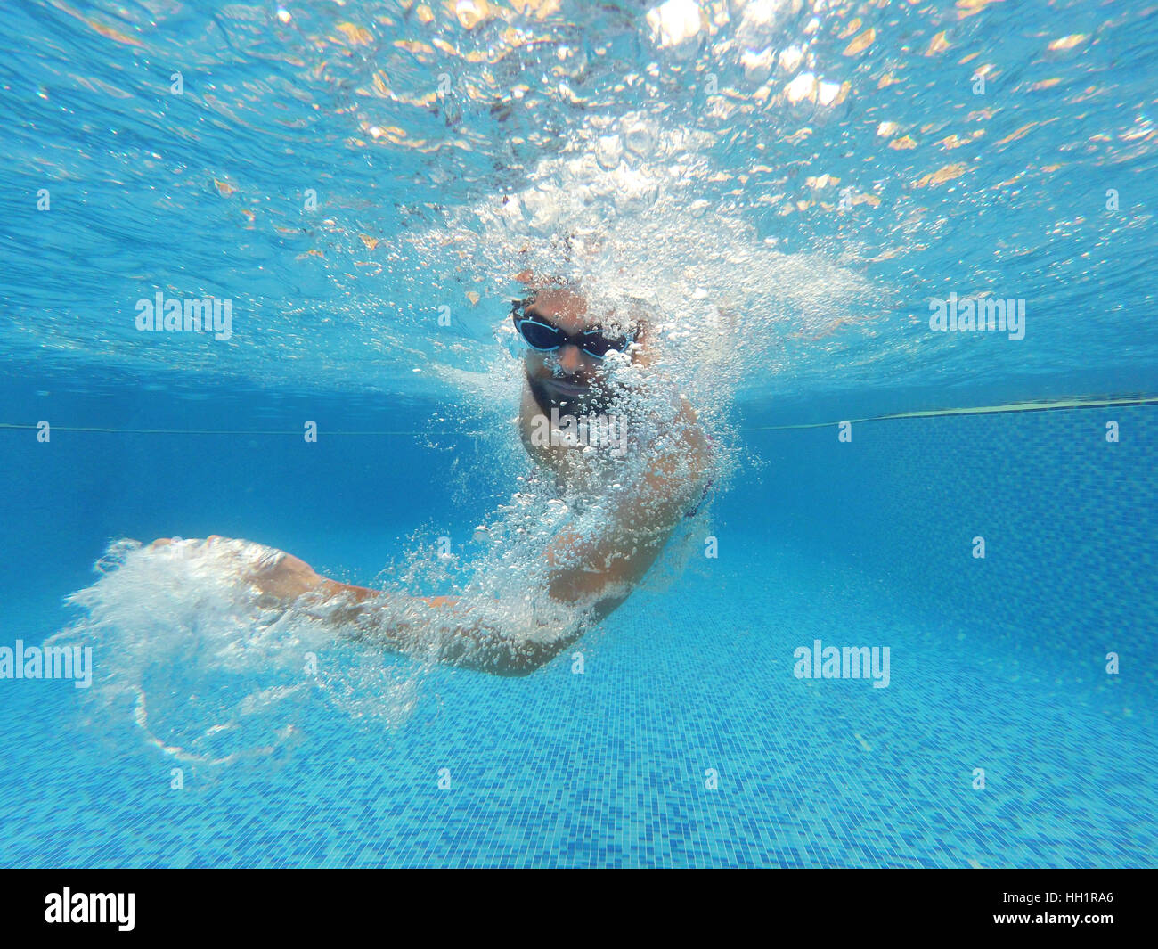 Junger Bart Mann mit Brille unter Wasser im Pool schwimmen Stockfoto
