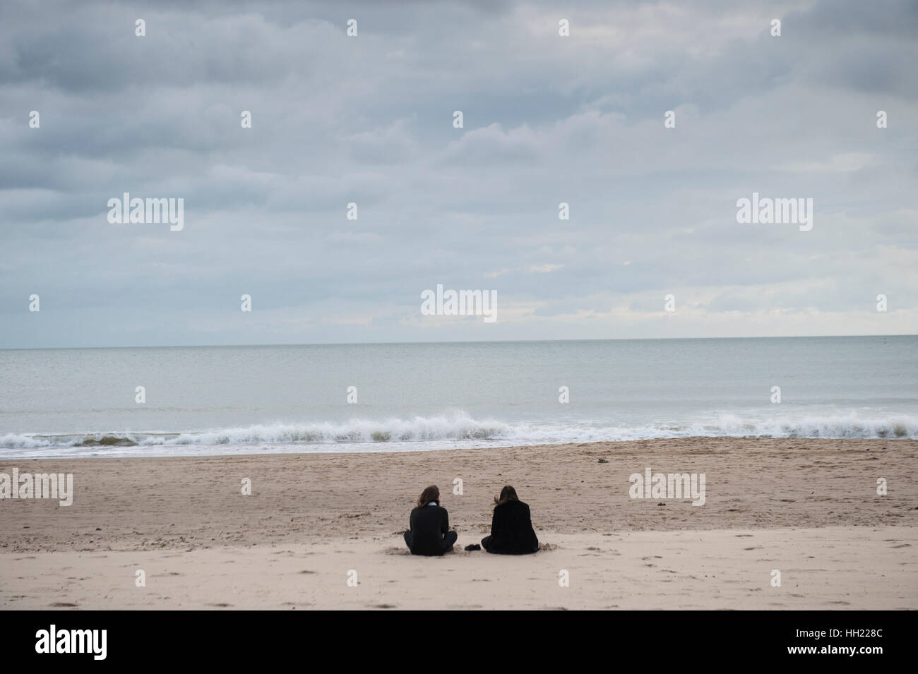 Zwei Menschen sitzen an einem Strand im winter Stockfoto