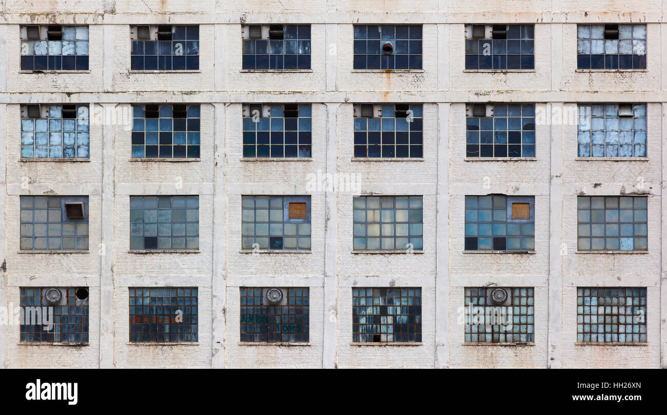 Windows in einer Fassade aus einem alten vernachlässigten Fabrikgebäude Stockfoto