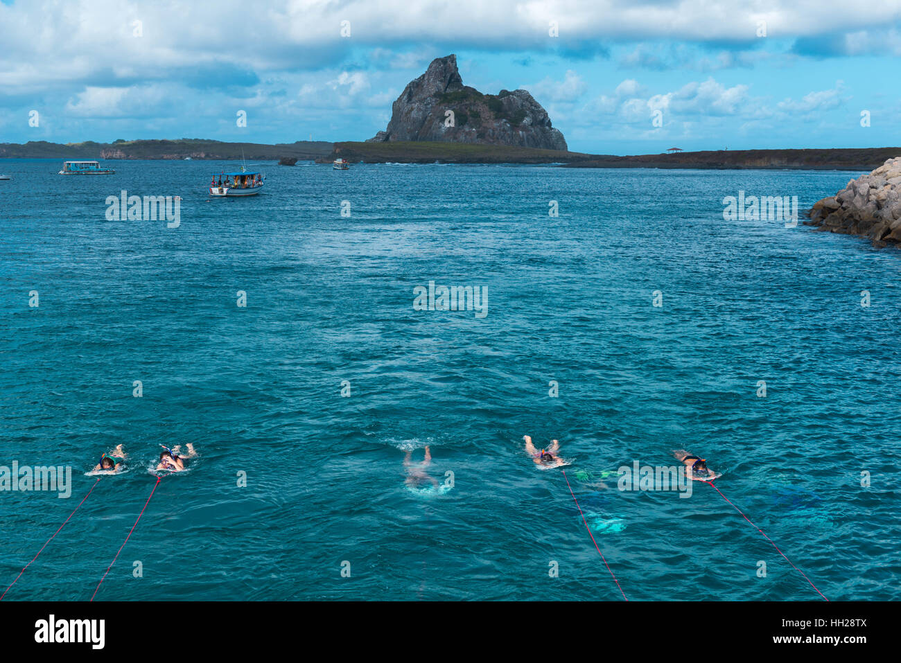 Touristen Schnorcheln vor der brasilianischen atlantischen Insel Fernando De Noronha, jeweils gezogen von einem Boot, Pernambuco, Brasilien Stockfoto