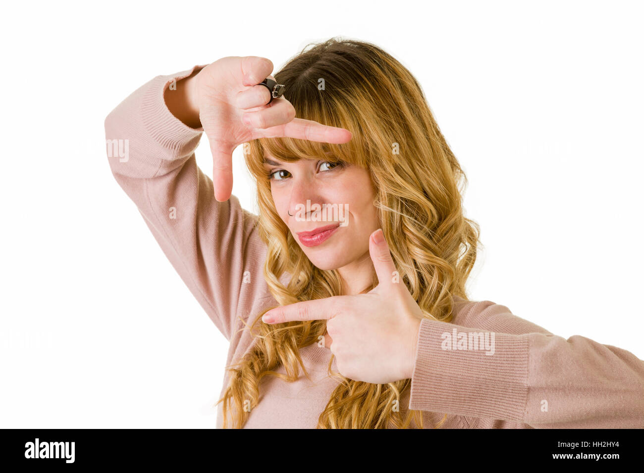 eine sehr attraktive blonde Frau ihr Gesicht mit den Fingern einrahmen Stockfoto