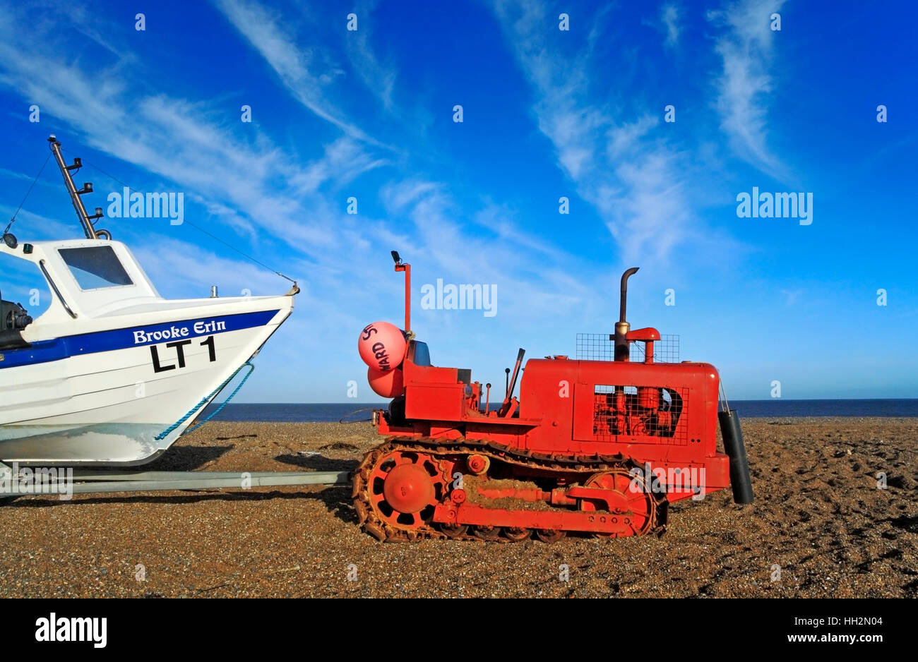 Rote Raupe Traktor, Anhänger und Küstenfischerei Boot am Strand von Cley nächstes Meer, Norfolk, England, Vereinigtes Königreich. Stockfoto
