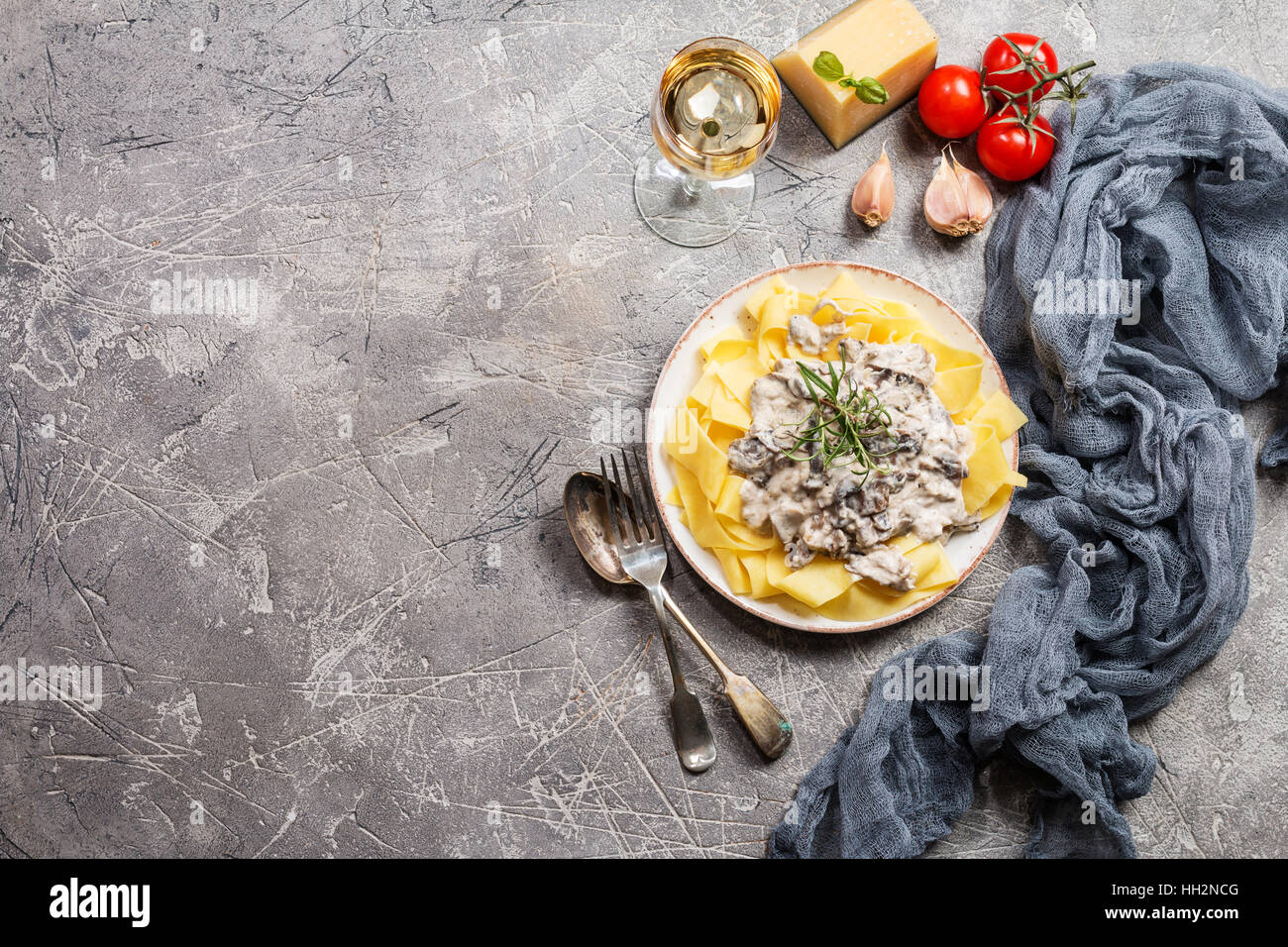 Frische Tagliatelle Pasta mit Pilzen in Rahmsoße in weißer Teller auf grauem Hintergrund, Ansicht von oben mit Textfreiraum Stockfoto