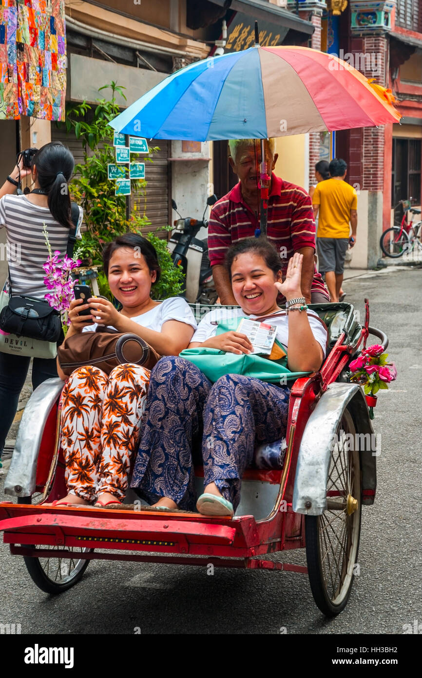 GEORGE TOWN, MALAYSIA - 24. Oktober: Mann fahren Rikscha mit zwei lächelnde Frauen in der Innenstadt von George Town. Oktober 2015 Stockfoto