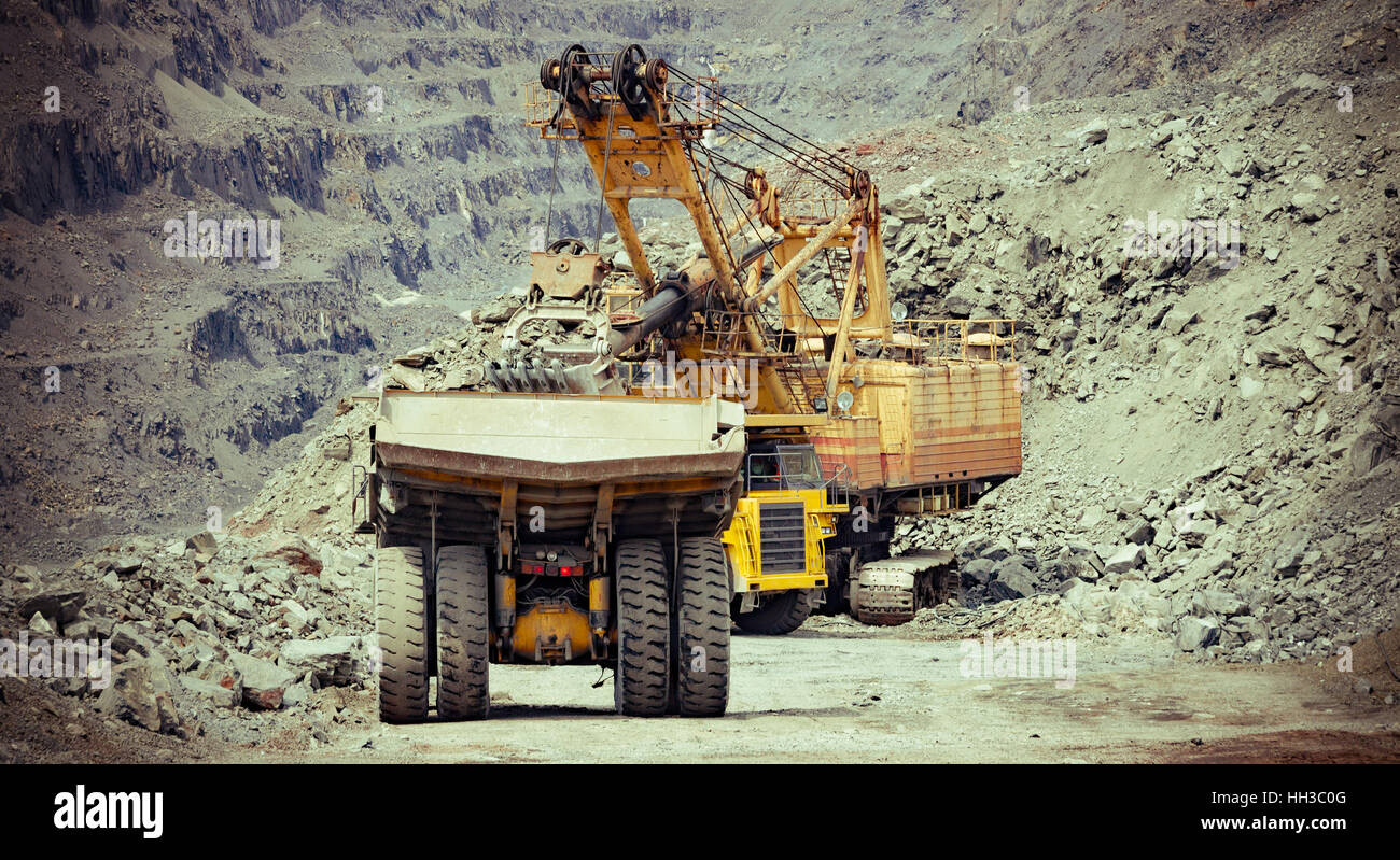 Schwere Muldenkipper und Bagger auf der Eisenerz Tagebau Baustelle arbeiten Stockfoto