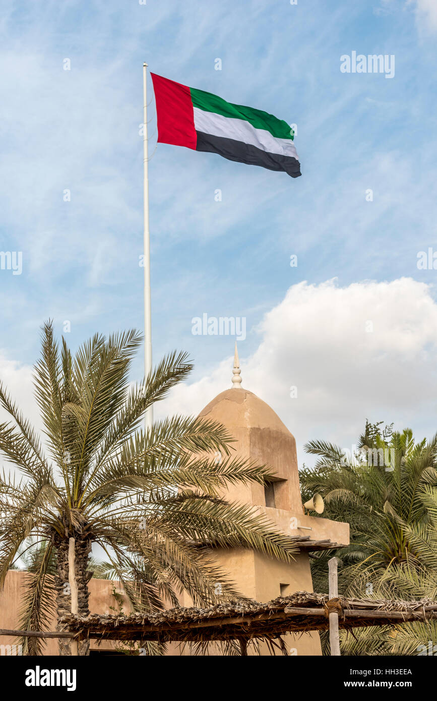 Flagge der Vereinigten Arabischen Emirate über alte Moschee.  Große Nationalflagge fliegen über eine alte Schlamm gebaut religiöse Gebäude in einem Golf-Land Stockfoto