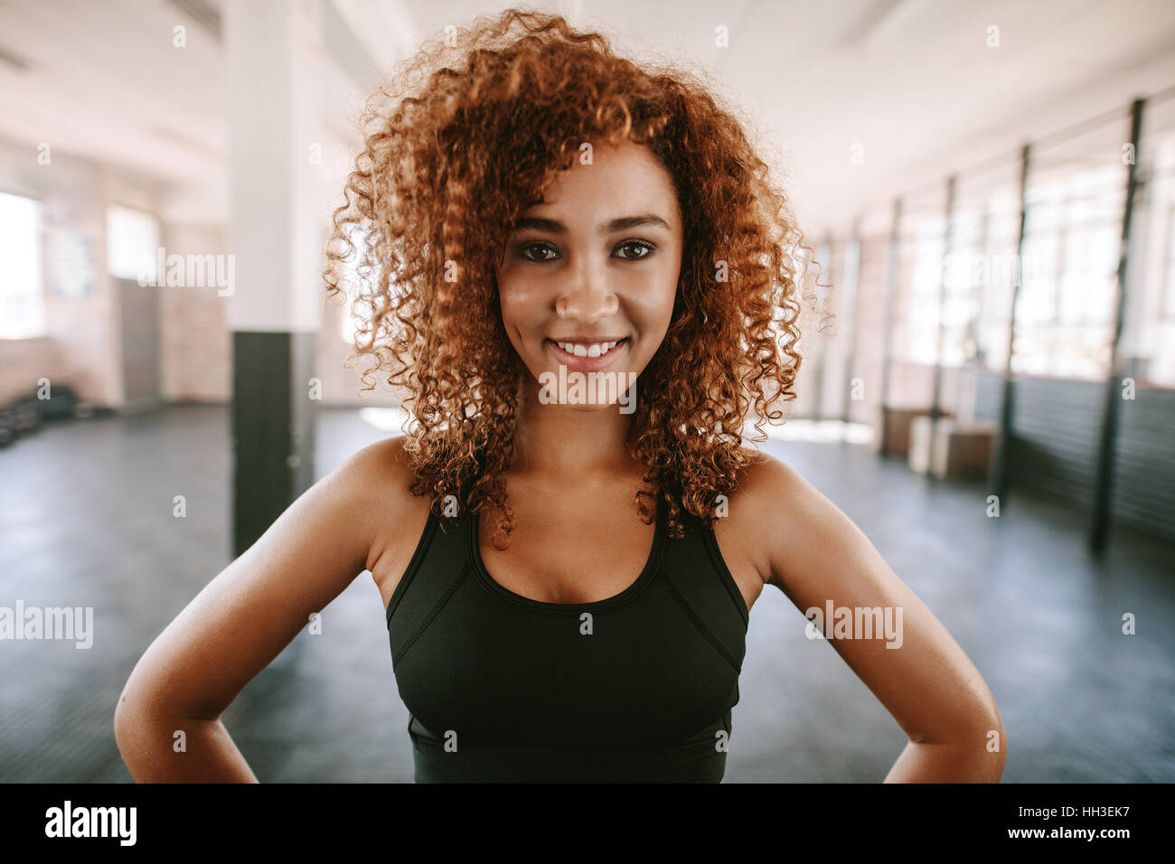 Portrait von junge afrikanische Frau mit lockigem Haar Lächeln im Health Club. Glücklich und schön Fitness-Frau im Fitnessstudio. Stockfoto