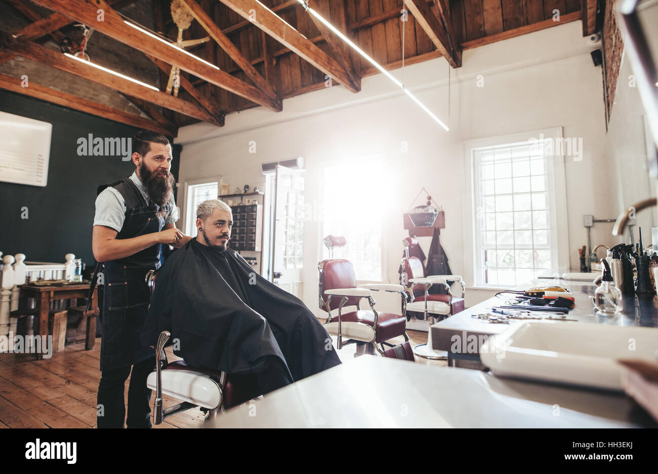 Junger Mann immer Haarschnitt beim Friseur. Friseur mit Kunden im Salon. Stockfoto
