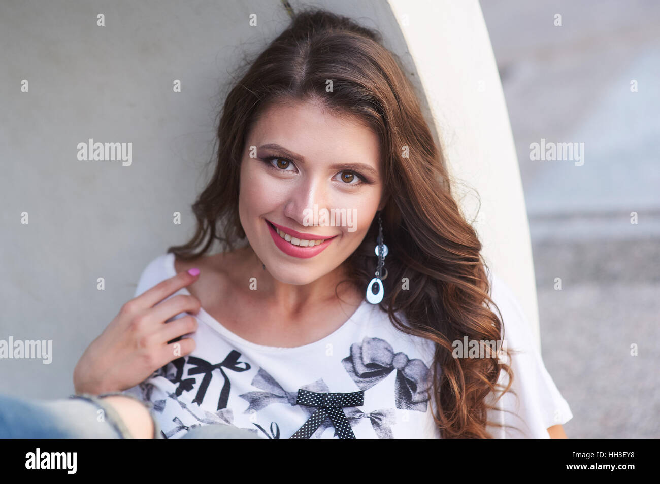lächelnde junge Frau in einem Hemd mit Make-up in der Nähe der Wand Stockfoto