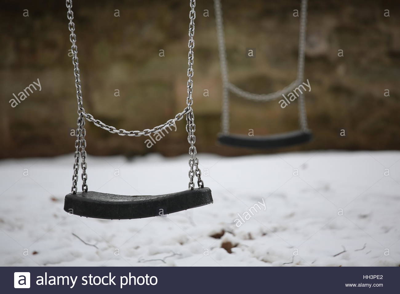 Schaukeln im Tageslicht im Winter hängen unbenutzt mit Schnee auf dem Boden Stockfoto