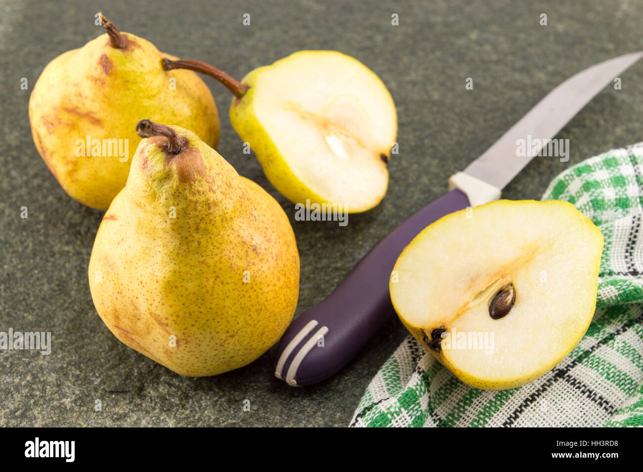 gelbe Birnen auf einem Tisch schneiden in der Mitte mit einem Messer Stockfoto