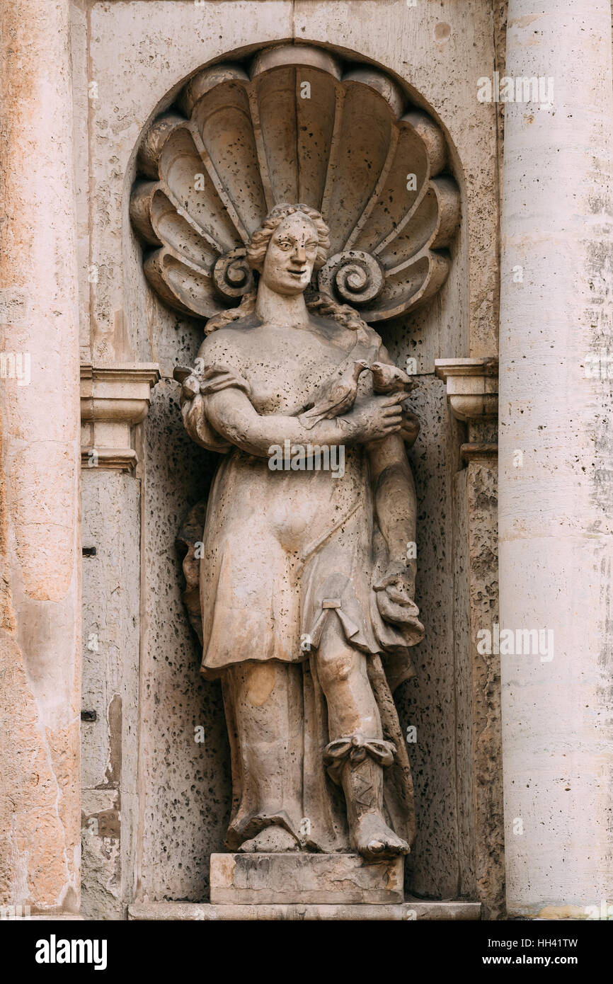 Riga, Lettland. Schließen Sie die Ansicht der Antike Statue der Frau mit zwei küssende Tauben In der Hand auf die Fassade der Kirche St. Peter, berühmte architektonische und Historiographie Stockfoto