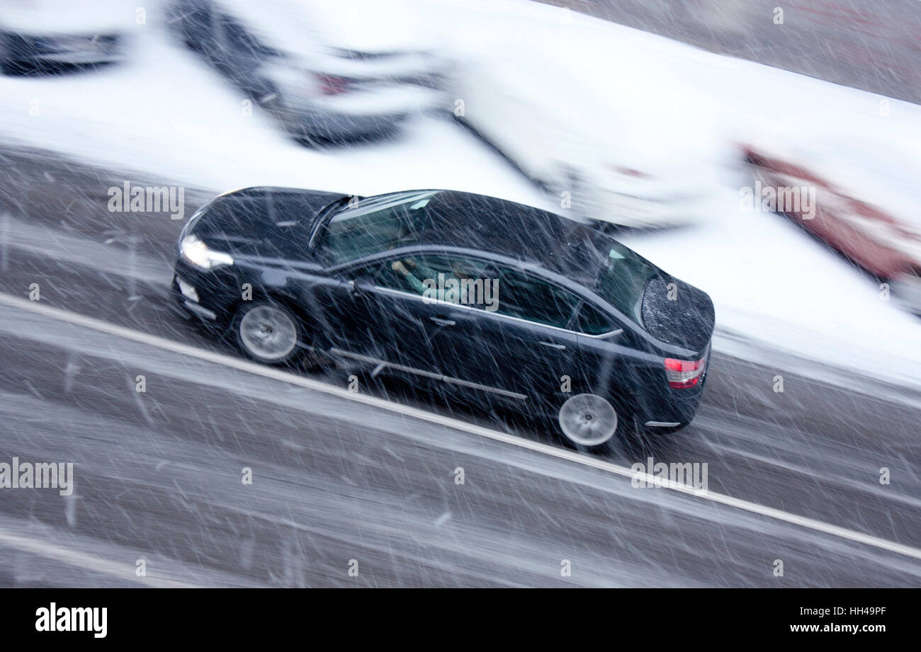 Verschneiter Tag in der Stadt: ein fahrendes Auto auf der Straße getroffen durch den schweren Schnee in Bewegung verwischen Stockfoto