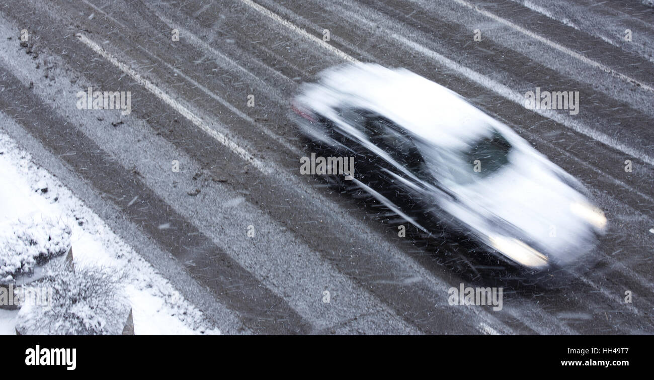 Verschneiter Tag in der Stadt: ein fahrendes Auto auf der Straße getroffen durch den Schneefall in Bewegung verwischen Stockfoto