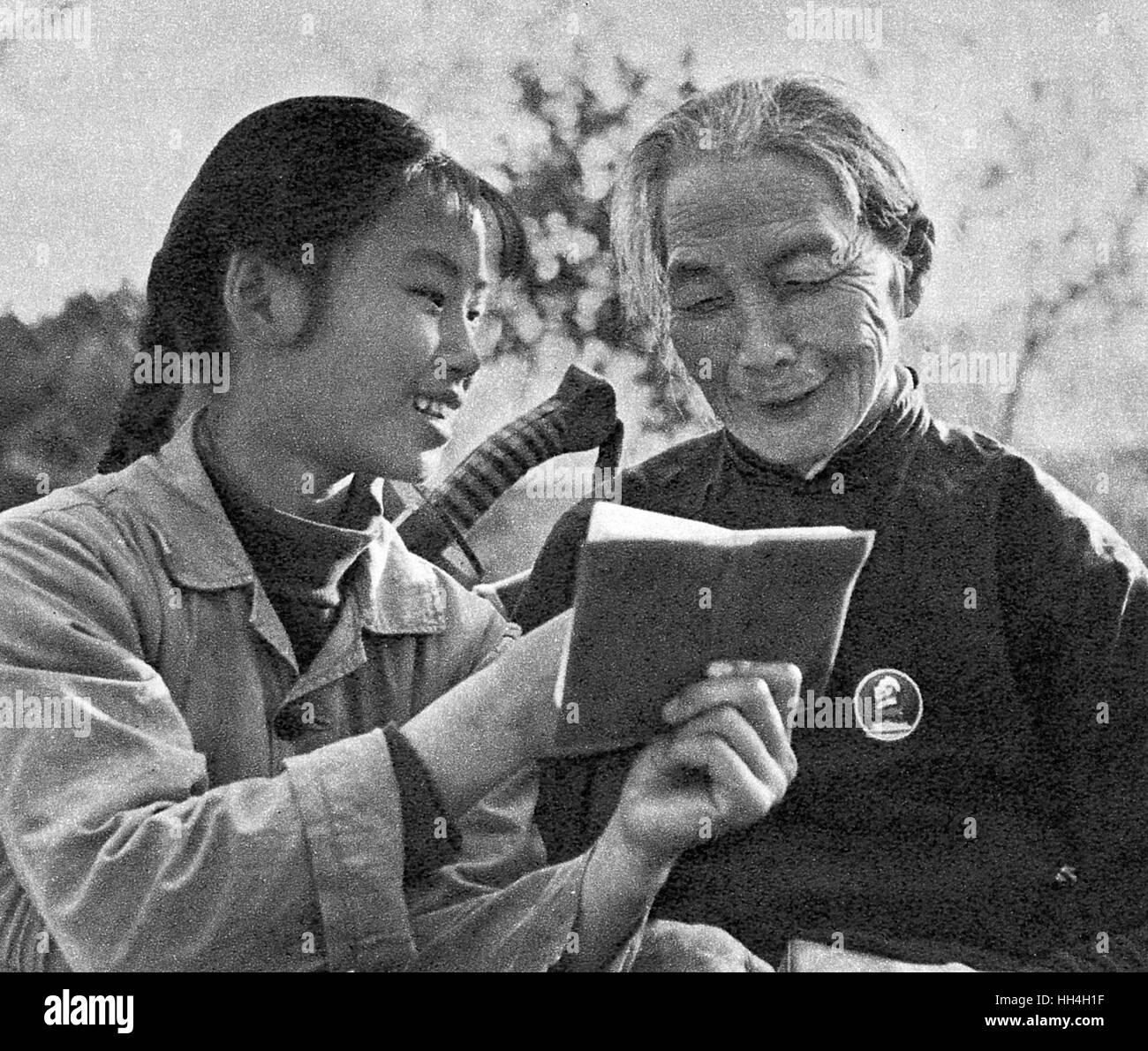 Junge Frau Mitglied einer Kommunikations-Team lesen Maos rote Büchlein mit einer armen Bäuerin zu Zeiten der Kulturrevolution im kommunistischen China, damit Lehre Alphabetisierung und Philosophie zugleich. Stockfoto