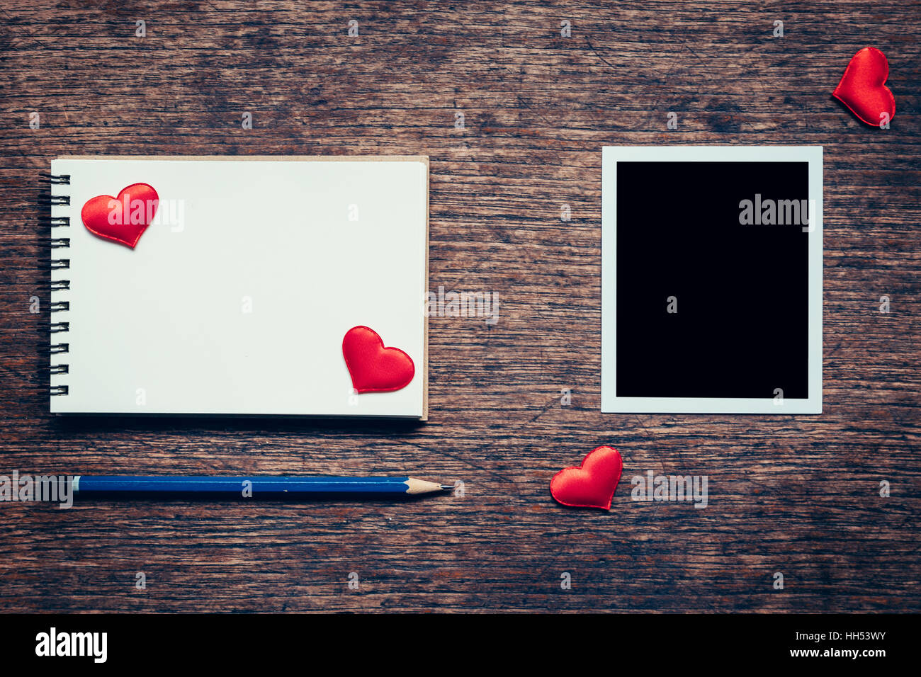 Leere Foto Frame, Notebook, Bleistift und roten Herz auf Holztisch Hintergrund. Stockfoto