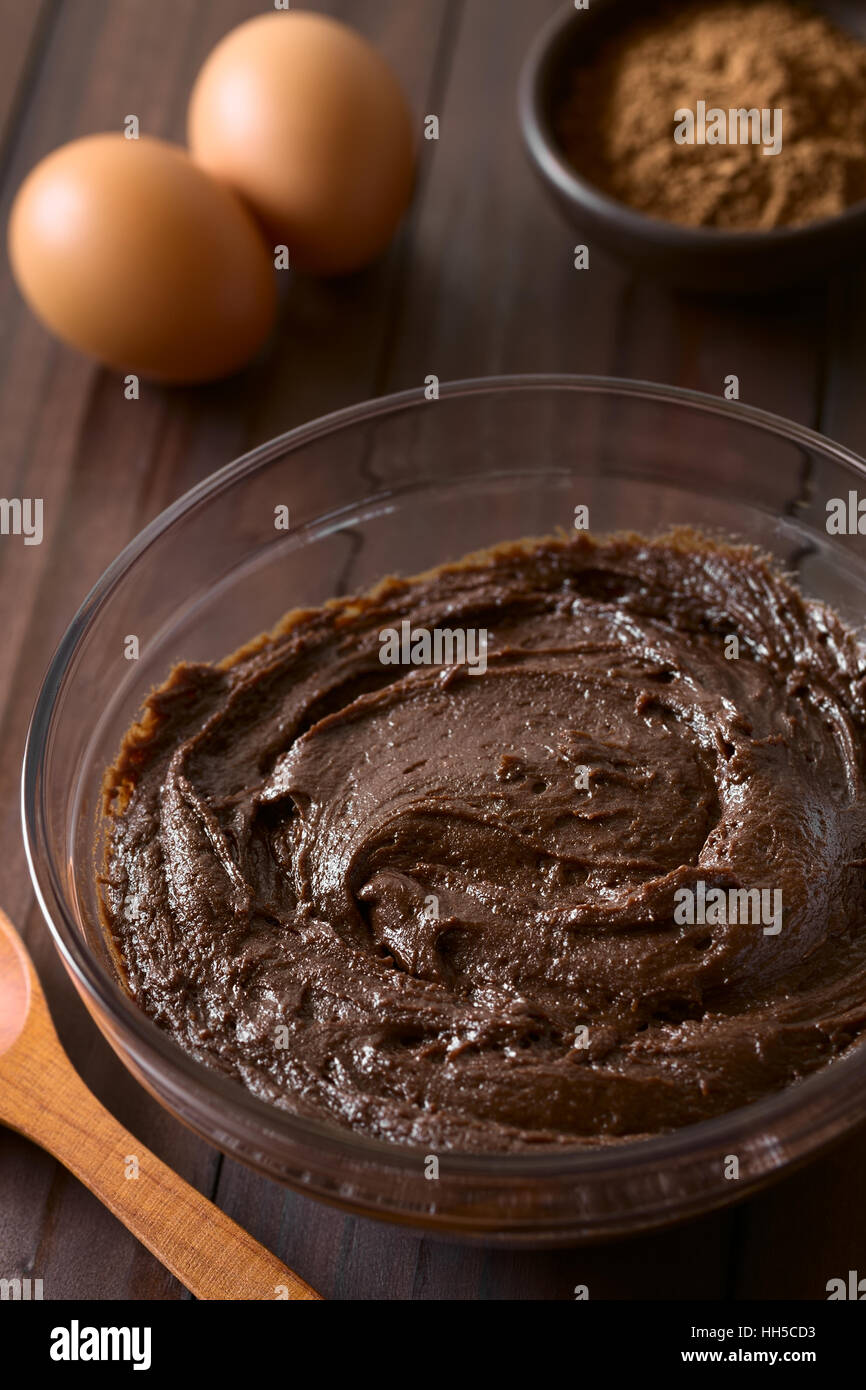 Grundlegende hausgemachten Brownie, Schokolade Kuchen oder Cookie-Teig in Glasschale mit Kakaopulver und Eiern in den Rücken Stockfoto