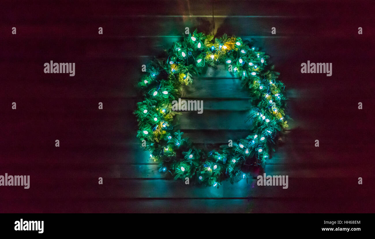 Adventskranz mit Weihnachtsbeleuchtung außerhalb an der Seite einer Scheune gefunden Stockfoto