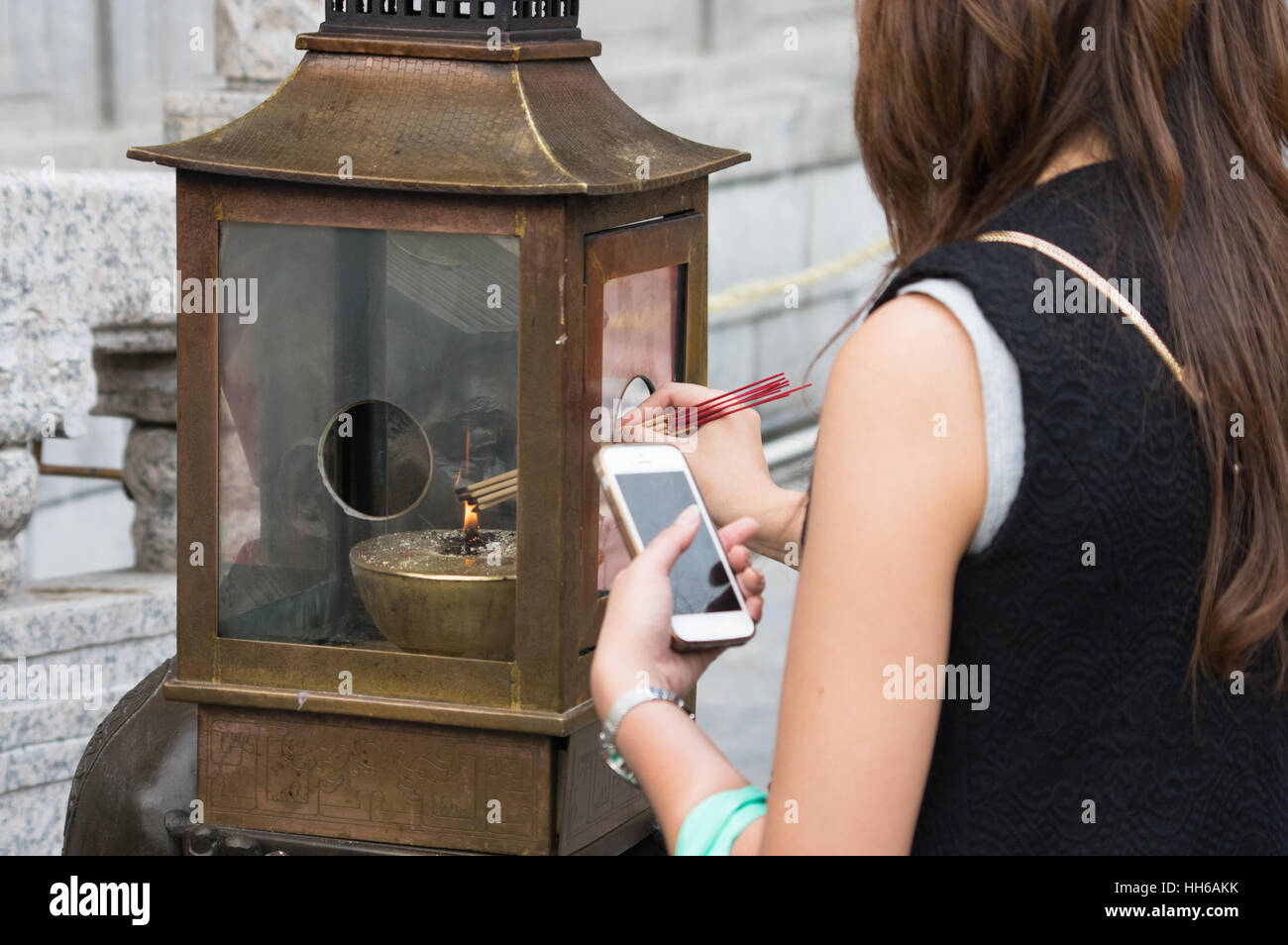 Frau mit Handy-Lichter Weihrauch klebt am Sik Sik Yuen Wong Tai Sin Temple, Hong Kong Stockfoto