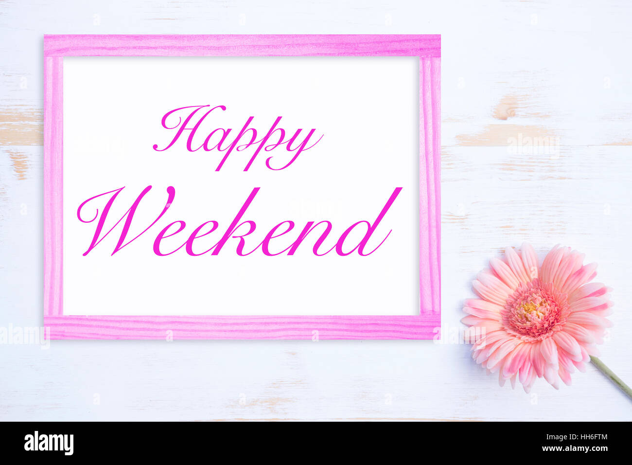 rosa Blume auf weißer Holztisch mit Rahmen und Worte Happy Weekend Stockfoto