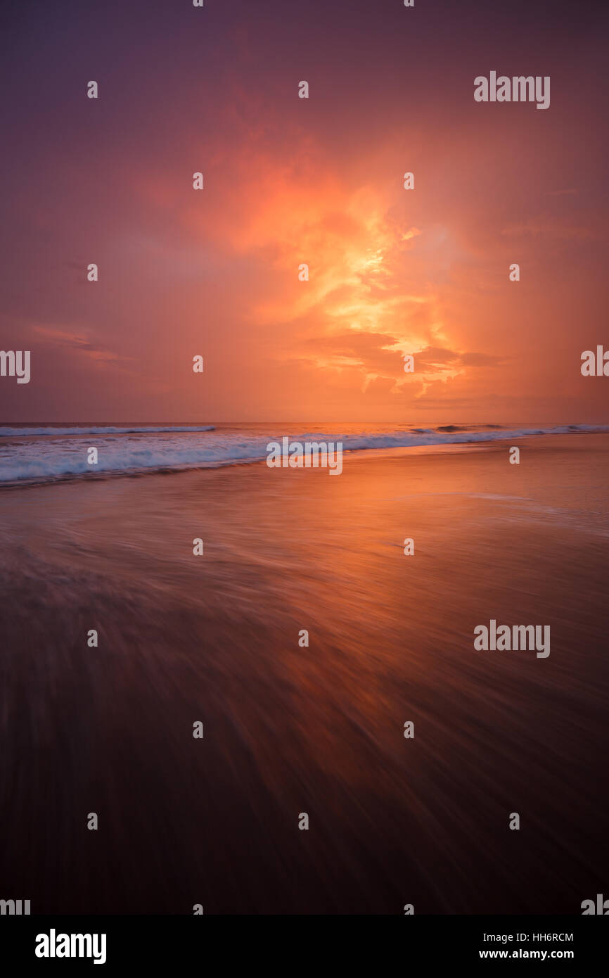 Sonnenuntergang und Wellen am leeren Strand Stockfoto