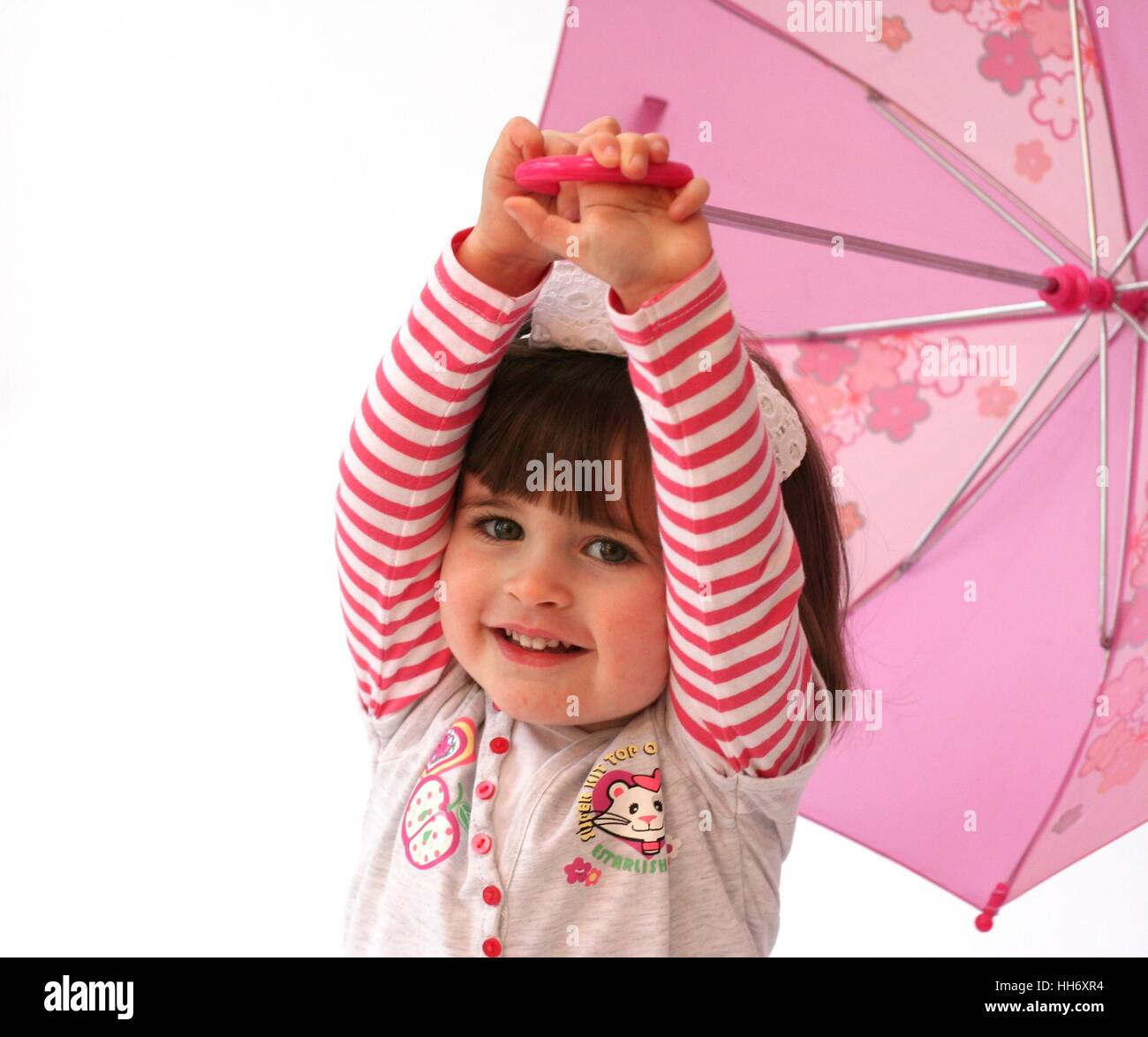 Kleine Mädchen spielen mit einem rosa Regenschirm mit den Armen in der Luft  spielen Zeit Kindheit stripy Fringe drei Jahr alt 3 Stockfotografie - Alamy