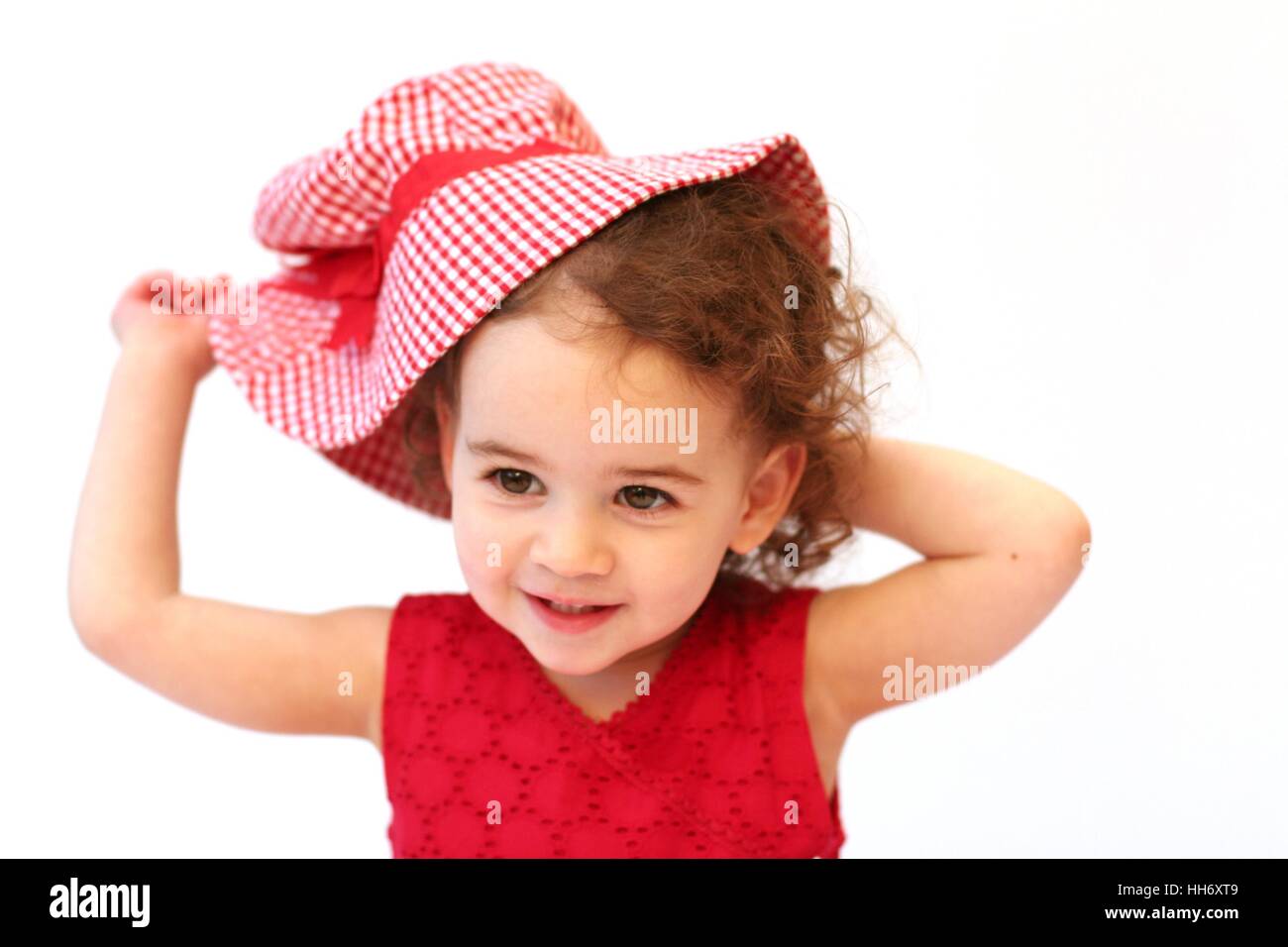 Süße Baby Mädchen Kind Kleinkind mit lockigem Haar spielen mit Rotem gingham Sonnenhut, Kindheit Konzept, unschuldig, Freude, happy Stockfoto