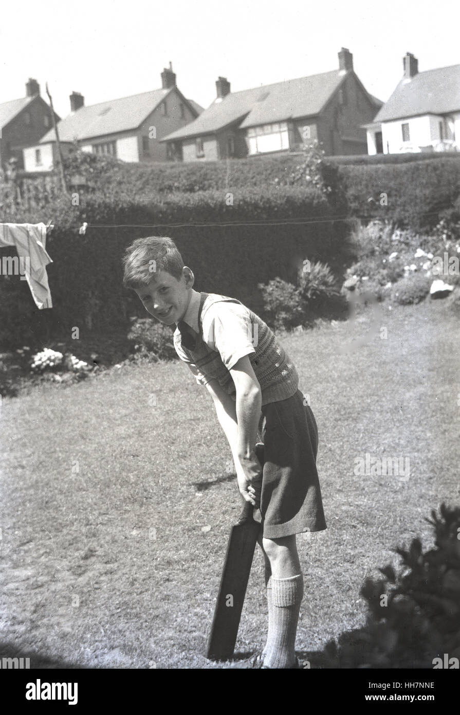 der 1950er Jahre shorts historische, junge junge tragen draußen im Garten mit seinen Kricketschläger. Stockfoto