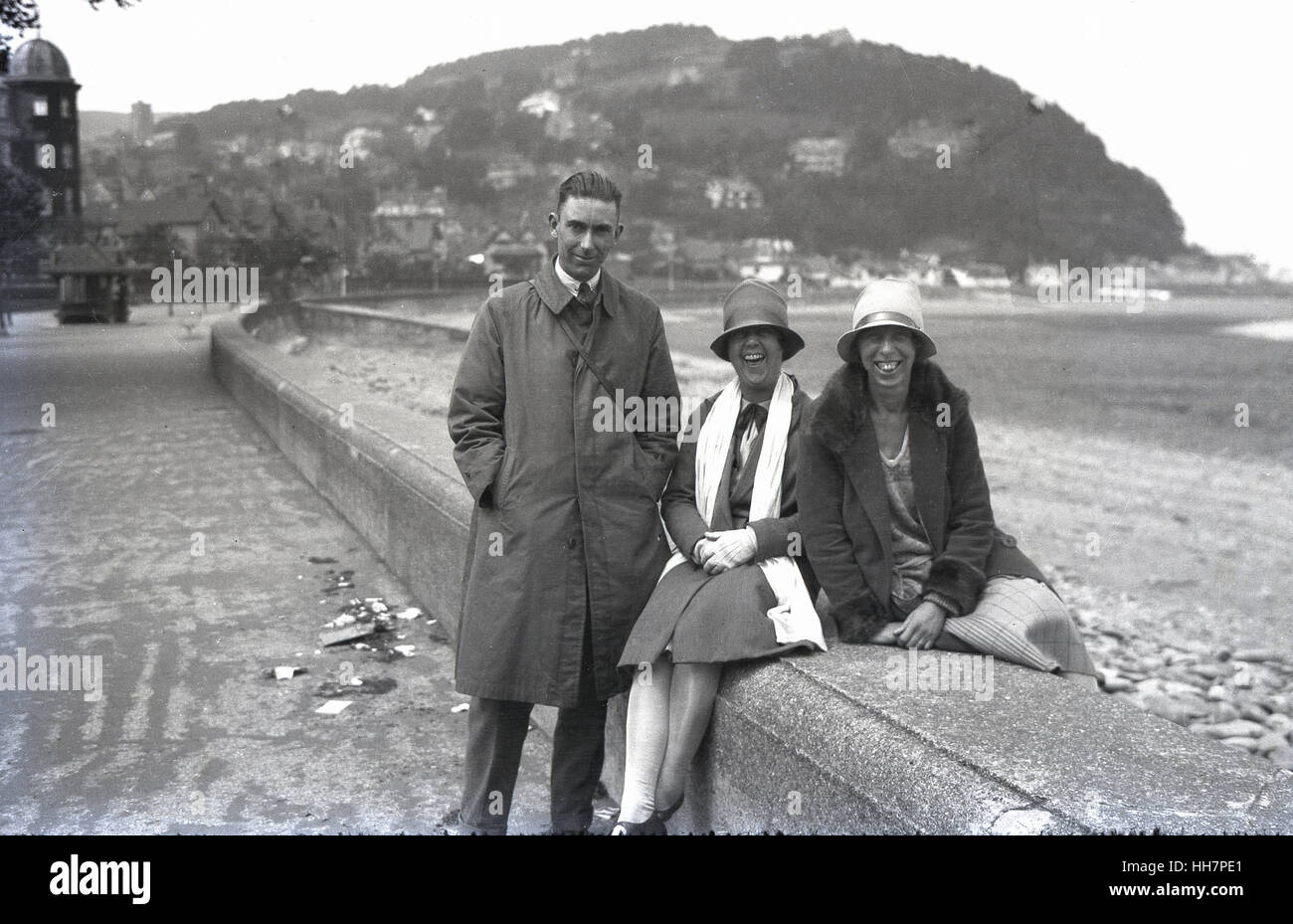 1920er-Jahren, historische, ein Gentleman zusammen mit zwei lächelnde Frauen sitzen auf einem Deich, glücklich, am Meer zu sein Stockfoto