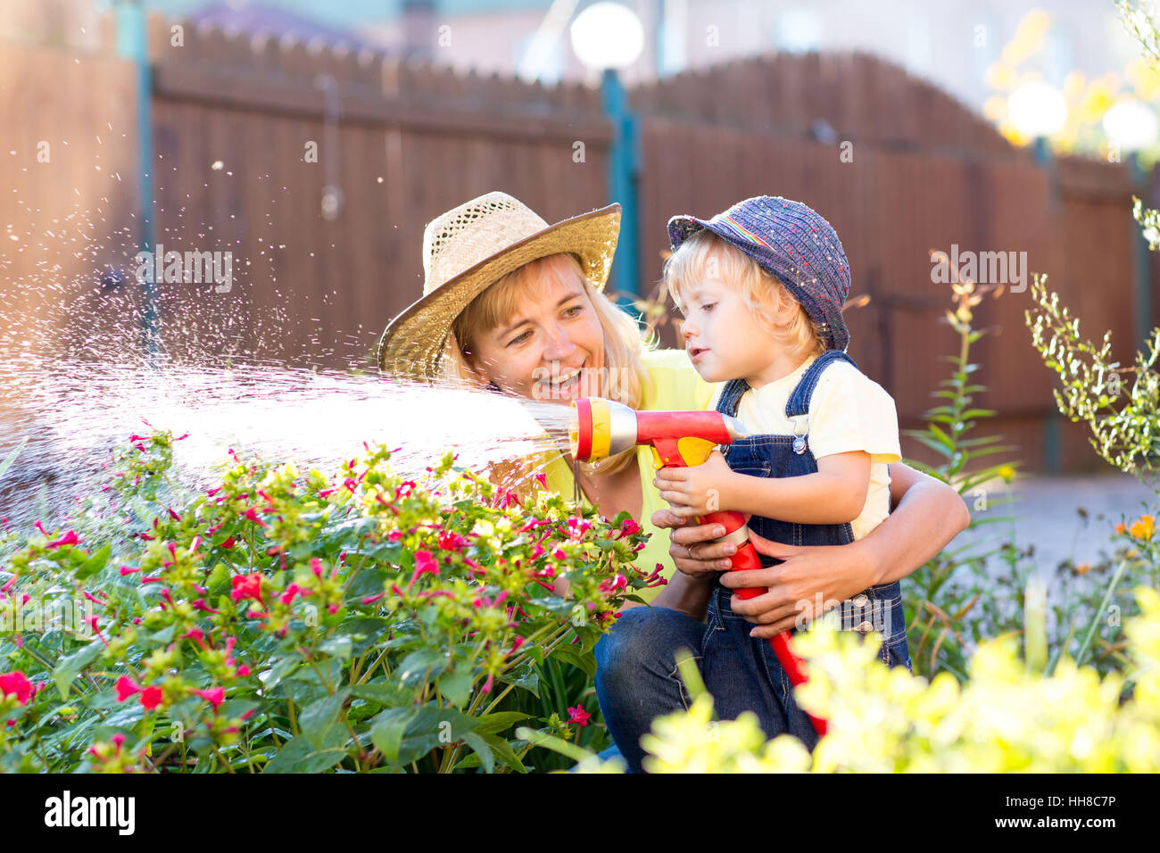 Glückliche Mutter und Kind, die Bewässerung im Hausgarten Stockfoto