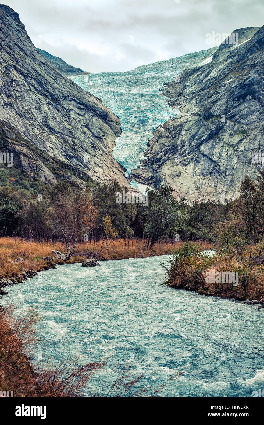 Briksdalsbreen Gletscher in Norwegen im Herbst. Gebirgsfluss aus geschmolzenem Eis im Vordergrund. Stockfoto
