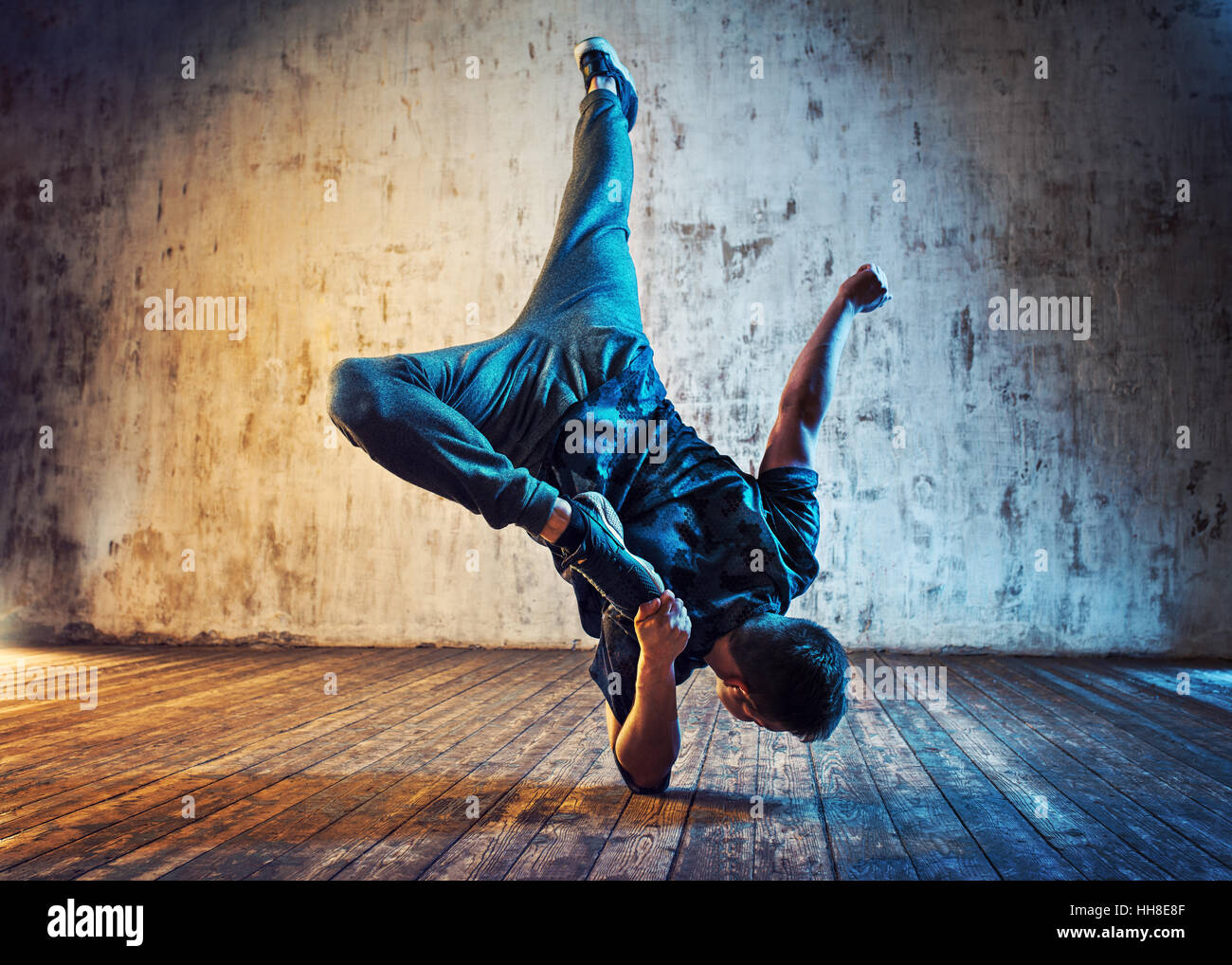 Junger Mann Breakdance auf Wand Hintergrund. Blaues und rotes Lichtereffekt. Stockfoto
