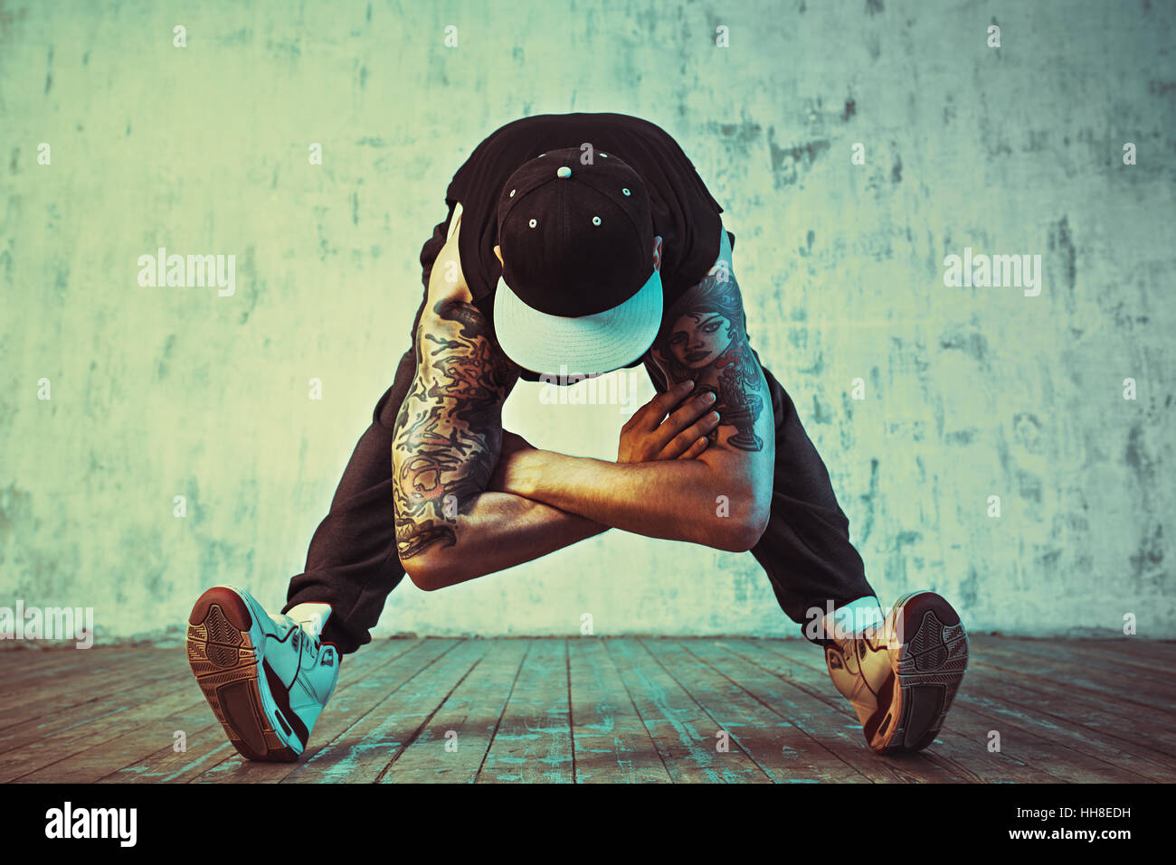 Junger Mann Breakdance auf Wand Hintergrund. Blaue und gelbe Farben Farbton. Tattoo auf den Körper. Stockfoto